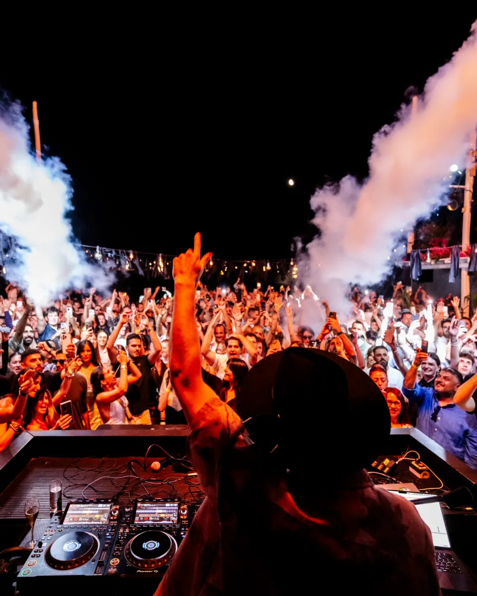 DJ facing the crowd as smoke cannons rise over the Island terrace
